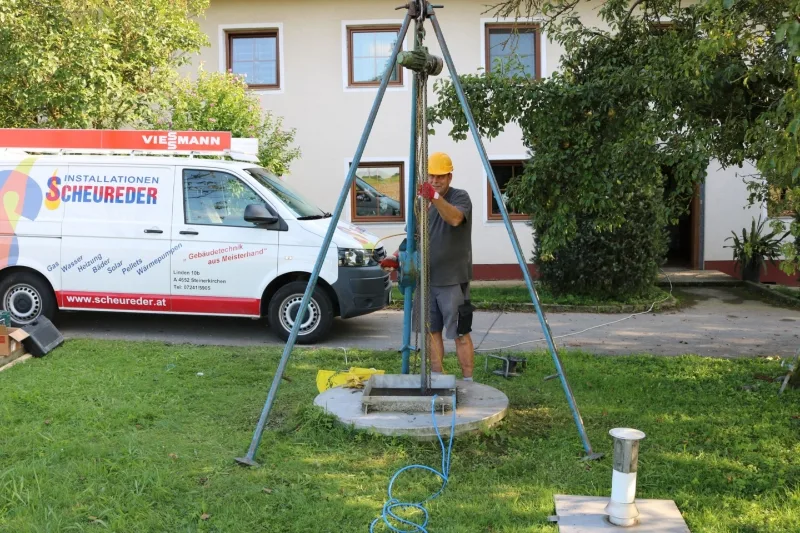 Brunnenbohrung im Hof, daneben der beschriftete Transporter des Betriebs