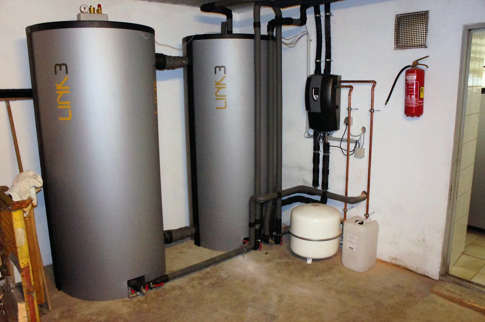 Heizraum mit zwei stehenden Pufferspeichern, gedämmten Leitungen und Ausdehnungsgefäß