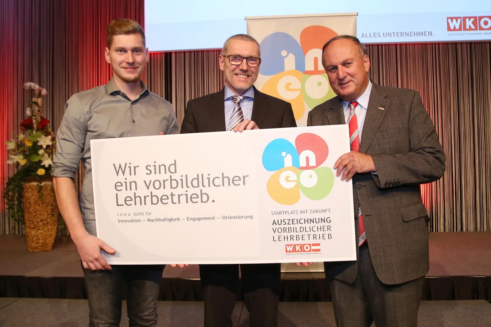 Übergabe der ineo-Auszeichnung, drei Personen halten die Tafel Wir sind ein vorbildlicher Lehrbetrieb