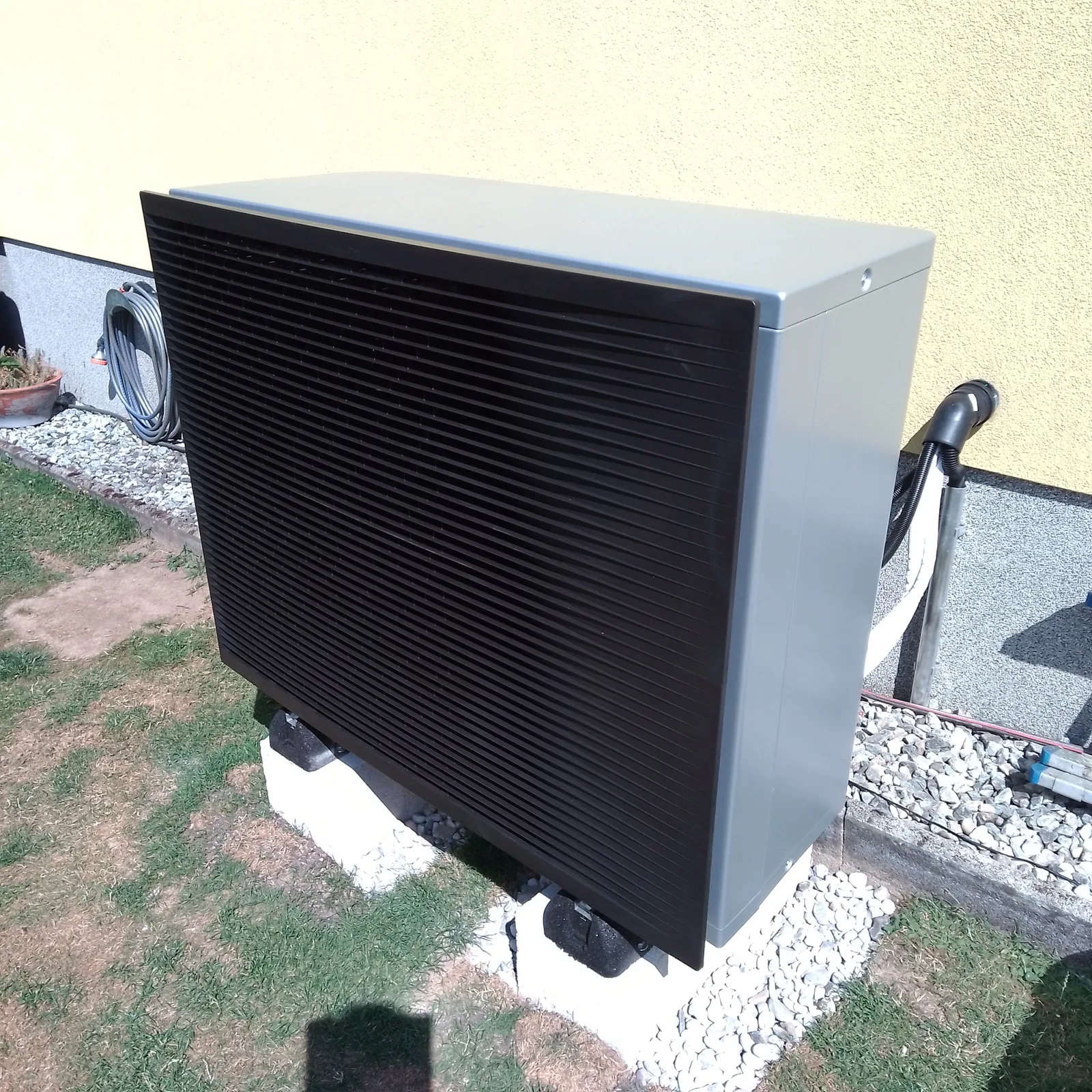 Wärmepumpe der Marke Daikin als Außeneinheit auf einem Betonsockel an der Hauswand